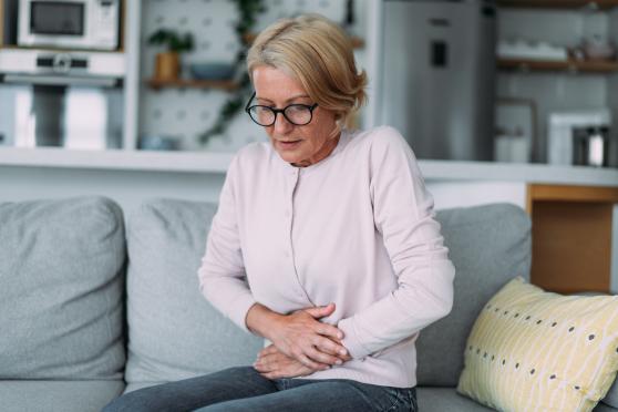 Woman sitting on sofa touching stomach